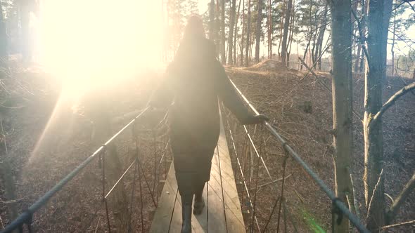Woman Walking On Suspension Bridge. Tourist Walkway In Forest. Traveler Explore Forest.Wooden Bridge