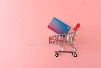 shopping cart with credit cart on pink background