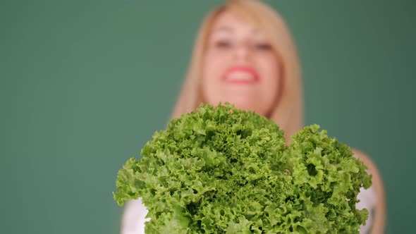 Pretty Woman Showing Lettuce at Green Background Closeup