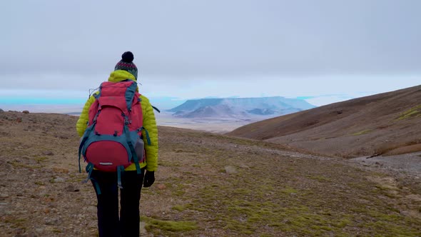 A Woman with a Backpack Walks in the Mountains