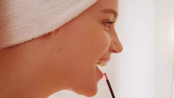 Woman applying lip gloss on her lips in bathroom