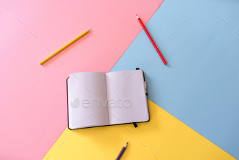 top view of Open notebook with blank pages and pencils on colorful background