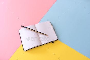 Open notebook with blank pages and pencil on colorful geometric background