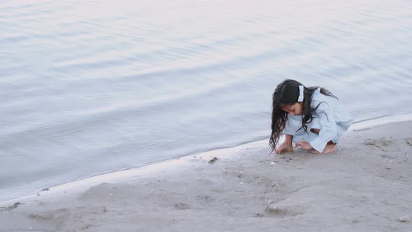 Lovely Girl Standing Near the Water on the Beach