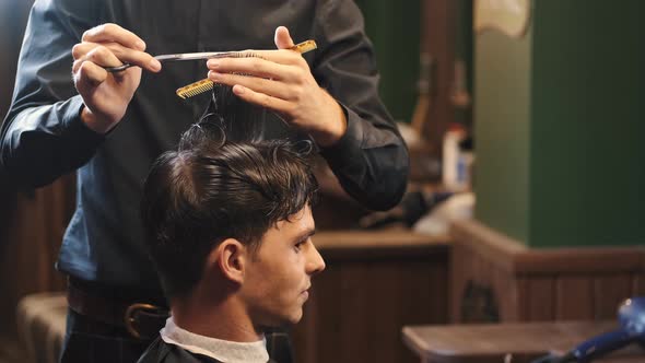 Barber Trimming Client's Hair Using Tools in Shop