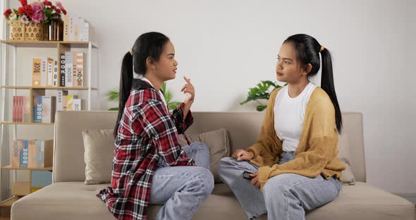 Asian twin girls talking and sitting on couch