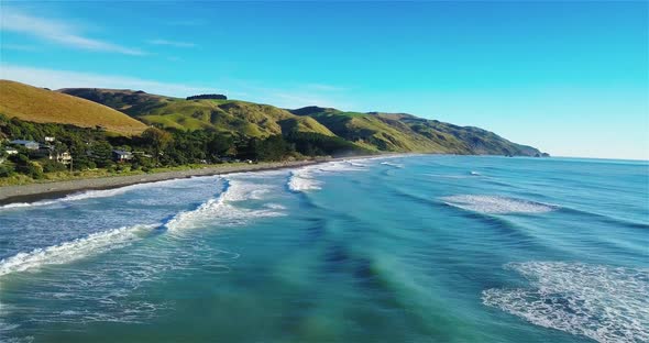 Drone View of the Beach of Gore Bay, New Zealand, with Green Farmland and Hills in the Background -