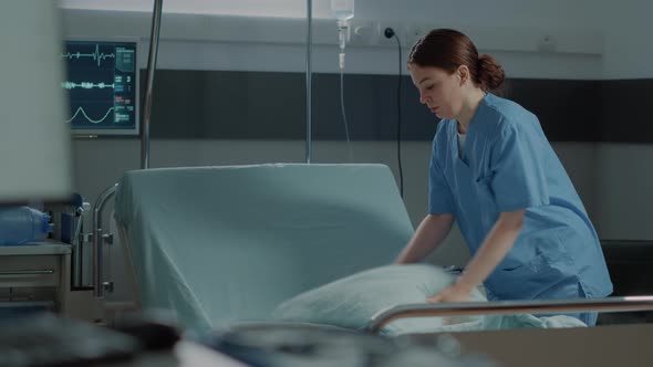 Medical Nurse Preparing Hospital Ward Bed with Pillow and Blanket