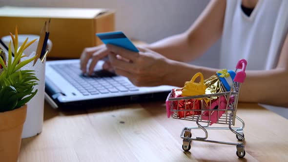 Young woman holding credit card and entering security code for payment online shopping at home