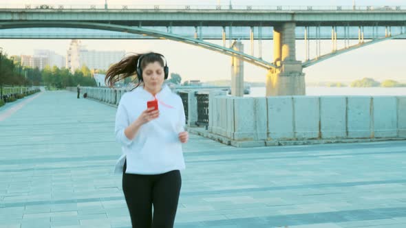 A Beautiful Girl in a White Sweater and Headphones Is Preparing for a Morning Run.