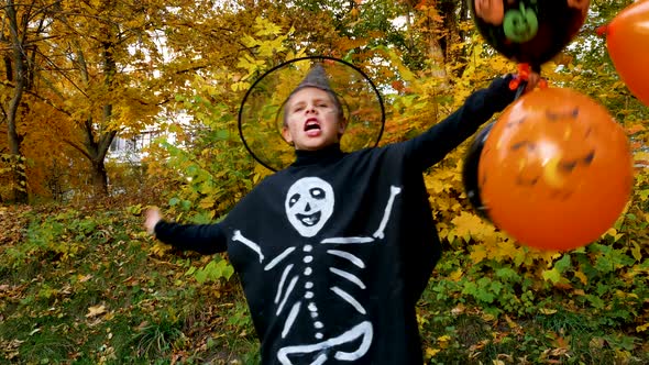 A Boy with Orange Black Inflatable Balloons in a Wizard Costume Waves His Hands During Halloween