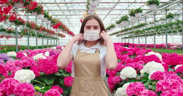 Smiling Woman Enjoying Incredible Flowerpots in Greenhouse