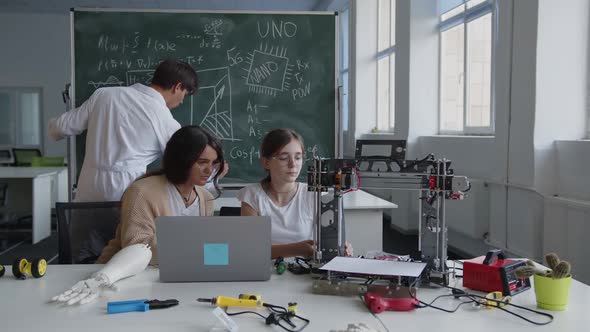 Girls Sits on the Chairs and Learns the Work of 3D Printer