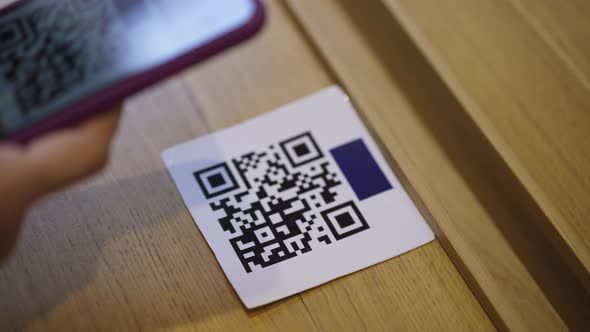 Closeup QR Code on Table with Female Hand Scanning Online Menu with Smartphone App in Restaurant