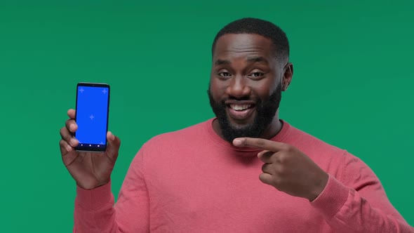 Happy Young Black Guy Showing His Phone Screen with Chroma Key and Pointing To It on Green Screen