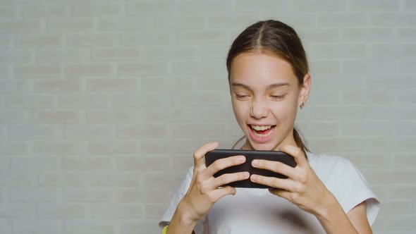 Teenager Girl Having Fun While Playing Video Game Touching Smartphone Screen