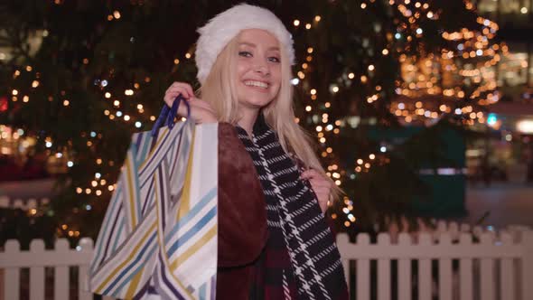 Young woman holds up her shopping purchase and twirls around and smiles