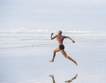 Woman in bikini sprinting on beach