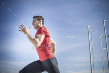 Young man sprinting against blue sky