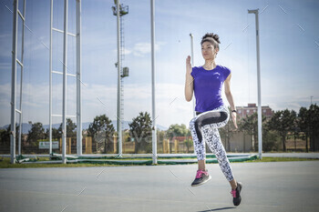 Young female sprinter sprinting at sport facility