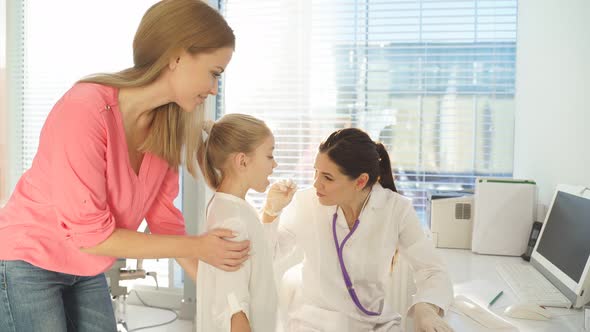 Young Female Doctor Examining Little Girl Mouth at Hospital Office