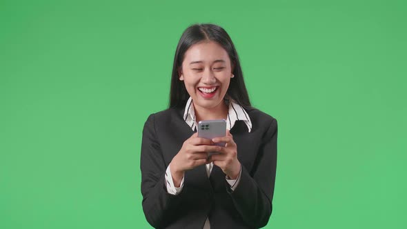 An Asian Business Woman Enjoy Using Mobile Phone While Standing On Green Screen In The Studio