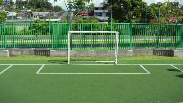 Zooming out at the goal of a football field with bright green artificial grass