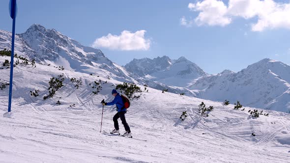 Male Skier Going Up the Slopes with Skies