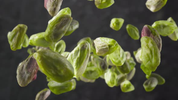 Flying of Peeled Pistachios in Dark Kitchen Background