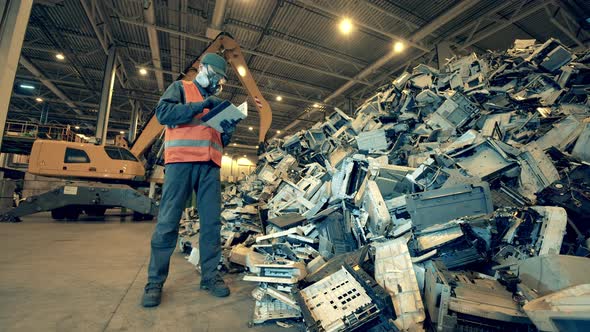 Debris of Office Machines Are Being Examined By the Junkyard Worker