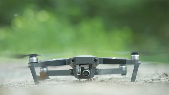 Drone copter with blurred propellers and video camera taking off from the ground.