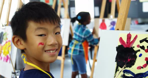 Portrait of schoolboy panting on canvas during drawing class