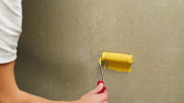 Painting Walls with Yellow Paint Using Roller Closeup