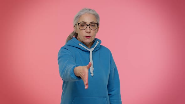 Friendly Senior Woman Outstretching Hand to Camera Offering Handshake Greeting with Kind Smile