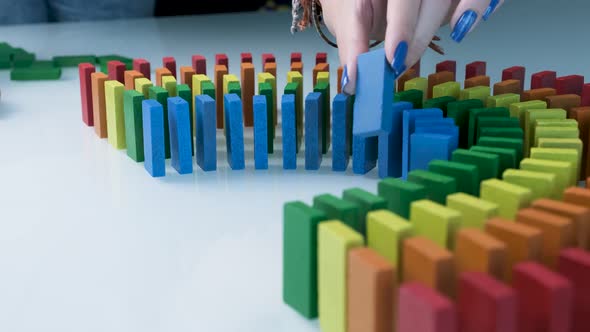 Line up of Dominoes in Rainbow Falling Colors with LGBT Colors of a Hand