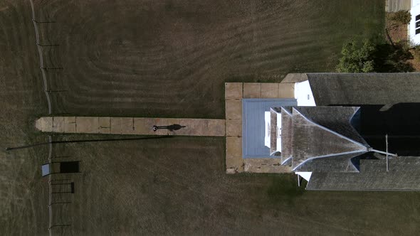 Still top-down aerial view of a person walking along narrow paved path and going to church. 90 degre