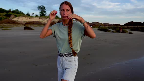 Long haired European female walking on sandy coastline, front view