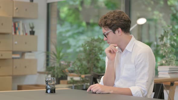 Young Man Thinking While Sitting in Office