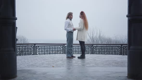 Long Shot of Stylish Man in Retro Style Shirt and Vest Bending Down on One Knee and Proposing