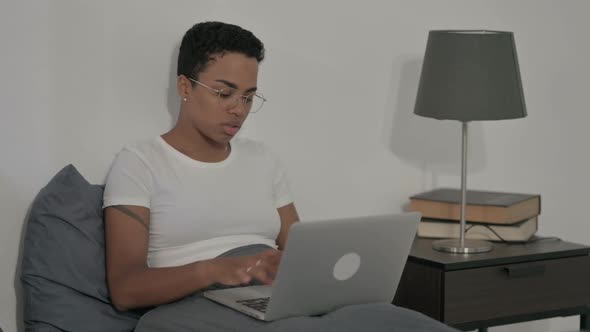 African Woman Working on Laptop in Bed