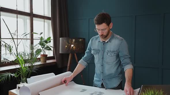 Close Up Shot of Young Man Hands Engineer Opening the Paper and Checking the Construction Drawings