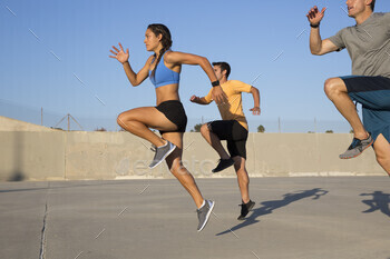 Three people sprinting with focus and determination on a sunny day