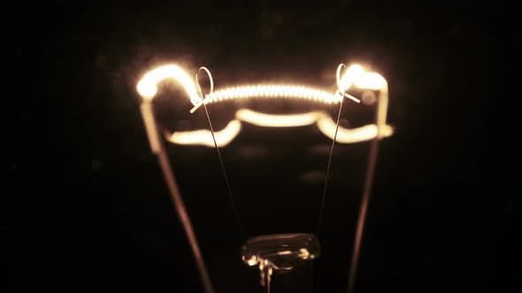 Tungsten Filament in a Glass Lamp Closeup in Slow Motion on Black Background