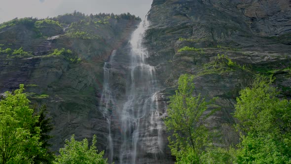 Stunning static shot of majestic waterfall fluent down the mountain in swiss region