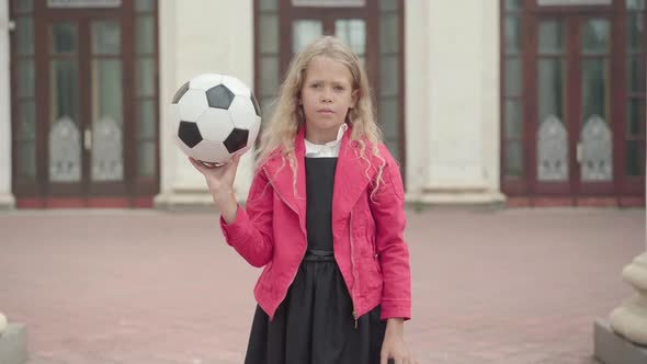 Pretty Blond Caucasian Girl Spinning Ball on Finger Outdoors. Portrait of Positive Confident