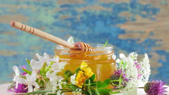 The Glass Jar with Fresh Honey Rotate Slowly on the Rustic Background