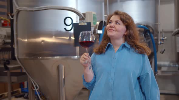 Master Winemaker with Glass of Red Wine in Modern Winery