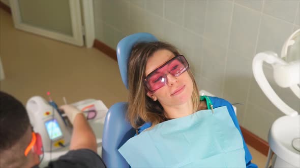 Female Patient with Protective Orange Goggles Sitting on Dental Couch