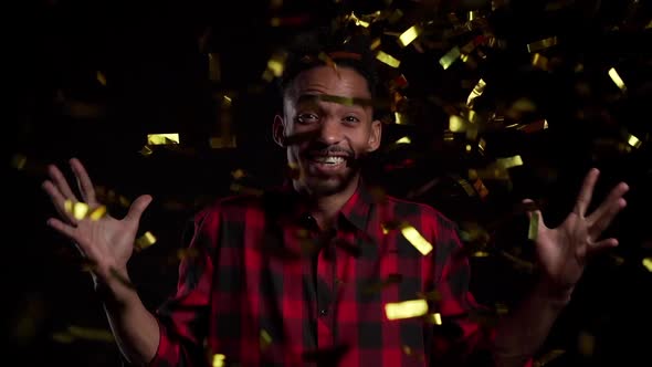 Surprised Excited African Man Winning, Having Fun in Confetti Rain on Black Background. 