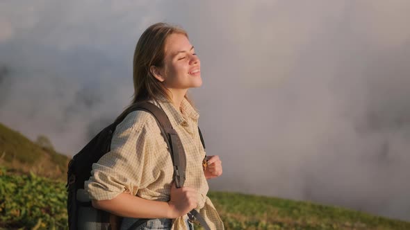 Happy Teenager Girl with Backpack is Admiring Natural Landscape at Top of Mountain